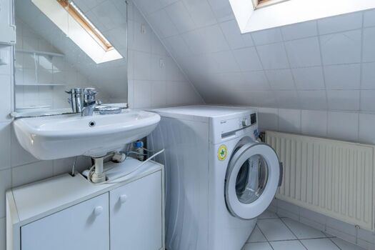 Badezimmer mit Waschmaschine, Dusche und WC