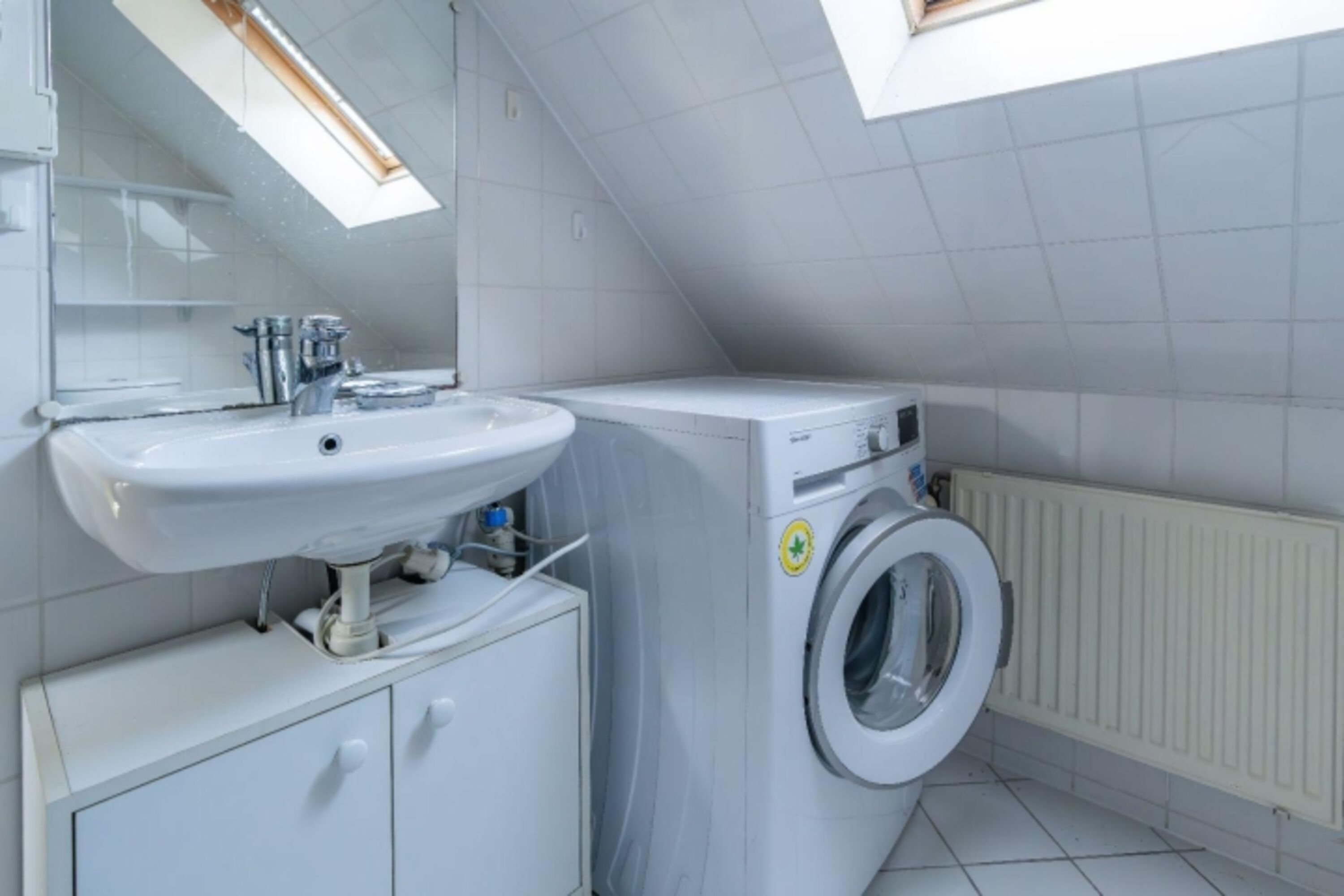 Badezimmer mit Waschmaschine, Dusche und WC