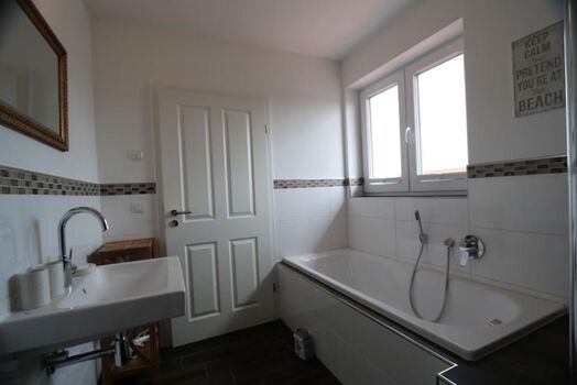 Bad der Kapitäns-Kajüte mit ebenerdiger Dusche mit Regenbrause und Badewanne.