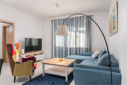 An open-plan living and dining area with comfy sofas, a smart TV, and a PlayStation 4.