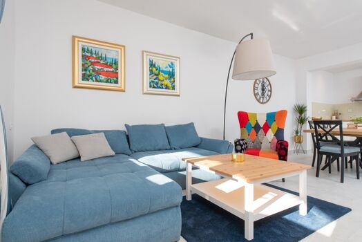 An open-plan living and dining area with comfy sofas, a smart TV, and a PlayStation 4.