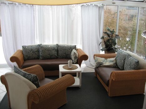 Der geräumige Wintergarten ist mit einer eleganten Korbmöbelgarnitur ausgestattet. Geniessen Sie auch gemütliche Abende vor dem offenem Kamin mit gleichzeitigem Blick über die Ostsee. Einmalig.