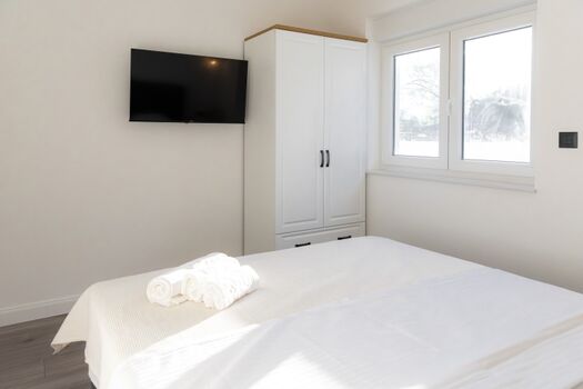 A bedroom with a queen-size bed, also equipped with air conditioning and a flat-screen TV.