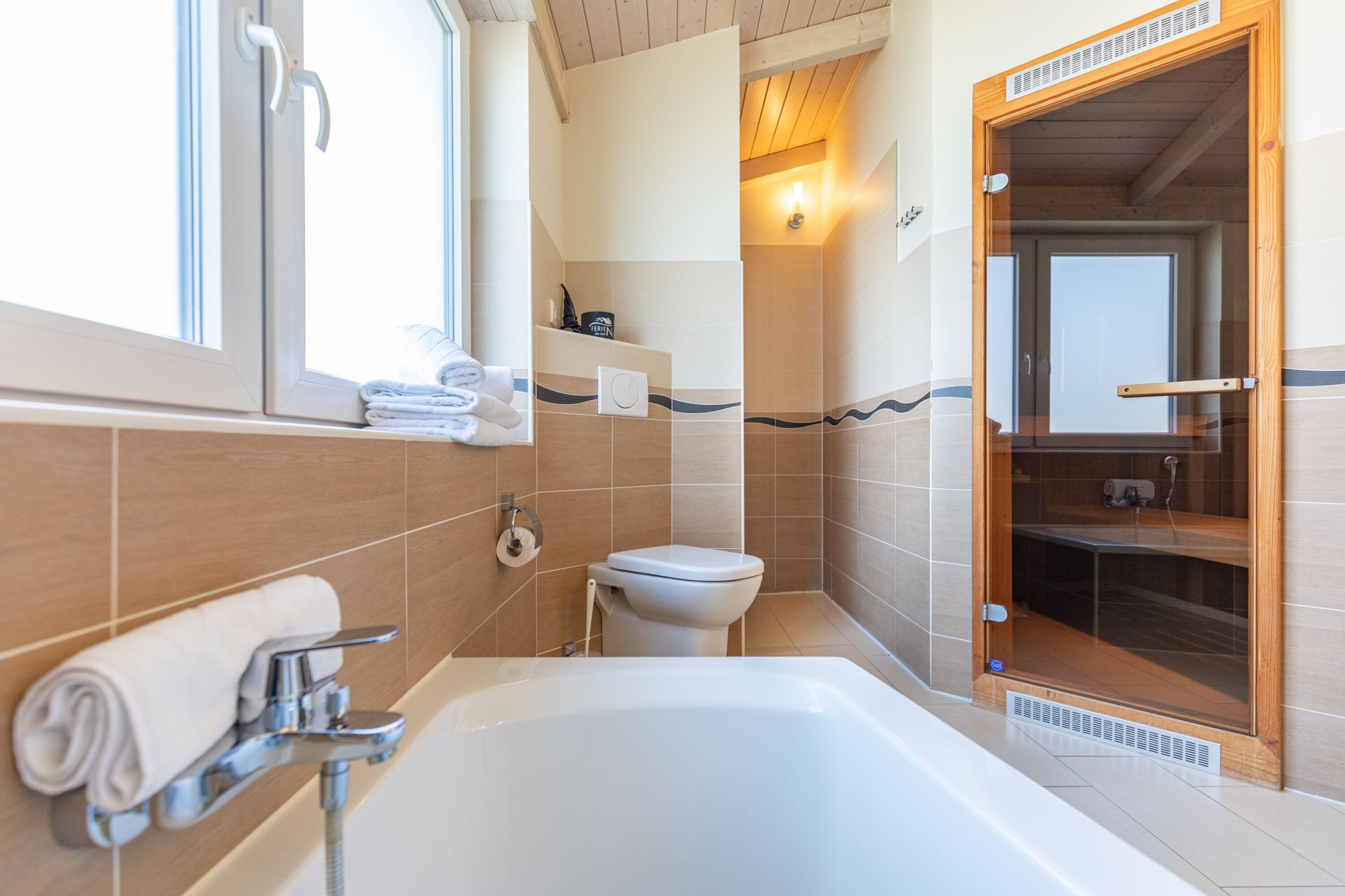 Ferienhaus Süderoog – Helles Badezimmer mit Badewanne und angrenzender Sauna