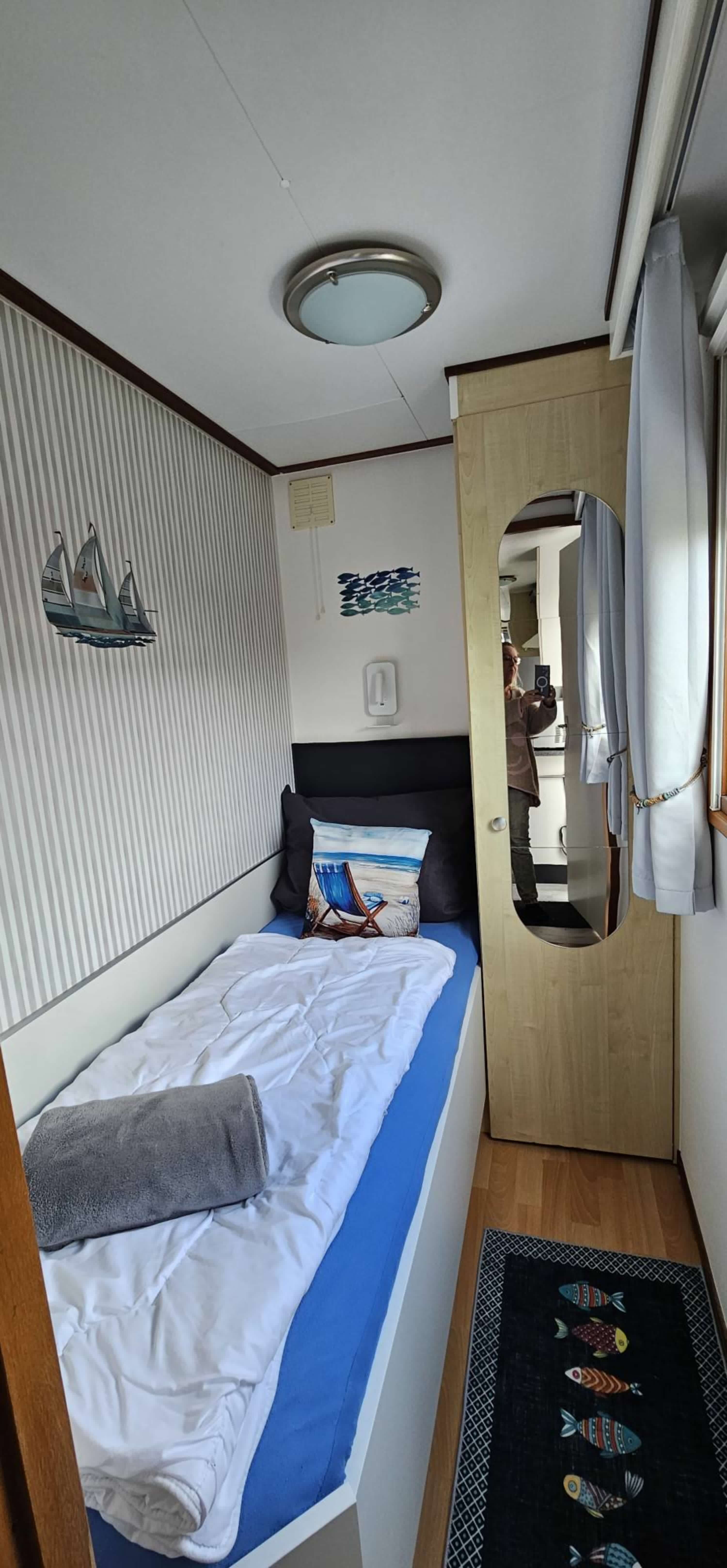 Einzelschlafzimmer mit Leselampe und Insektenschutz sowie Verdunkelungsrollo