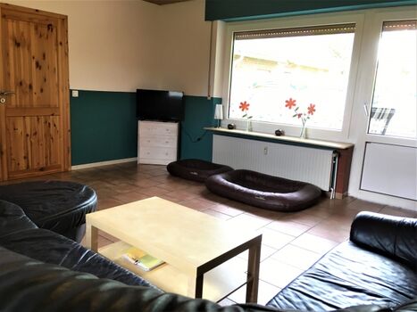 Das Wohnzimmer mit großer Ledereckcouch und Zugang zum Garten