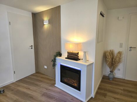 Gemütliches Wohnzimmer mit Couch und elektrischem Kamin
