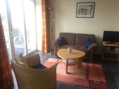 Das Wohnzimmer mit seitlichem Meerblick durch eine Baumreihe