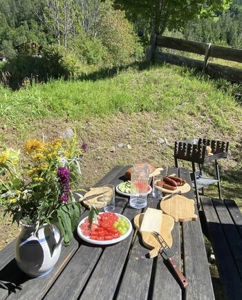 Ein entspannter Genussmoment im Berggarten: friesch zubereitete Speisen auf dem Tisch im Freien, umgeben von Natur und Ruhe rund um das Ferienhaus Mildner