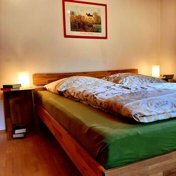 Ein Schlafzimmer zum Ankommen und Abschalten: warmes Licht, ein komfortables Bett und kleine Details wie Büche auf den Nachtischen schaffen eine ruhige , behagliche Atmosphäre
