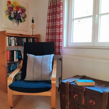Die liebevoll gestaltete Leseecke im Schlafzimmer bietet einen ruhigen Rückzugsort mit Sessel und ausgewählter Lektüre für entspannte Auszeiten.