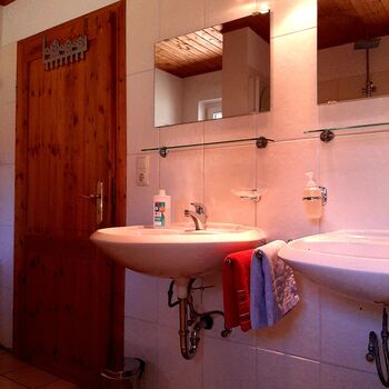 Das Badezimmer im Ferienhaus Mildner mit Doppelwaschbecken, hochwertigen Holzdetails und gepflegter Ausstattung, funktional, sauber, und harmonisch gestaltet.