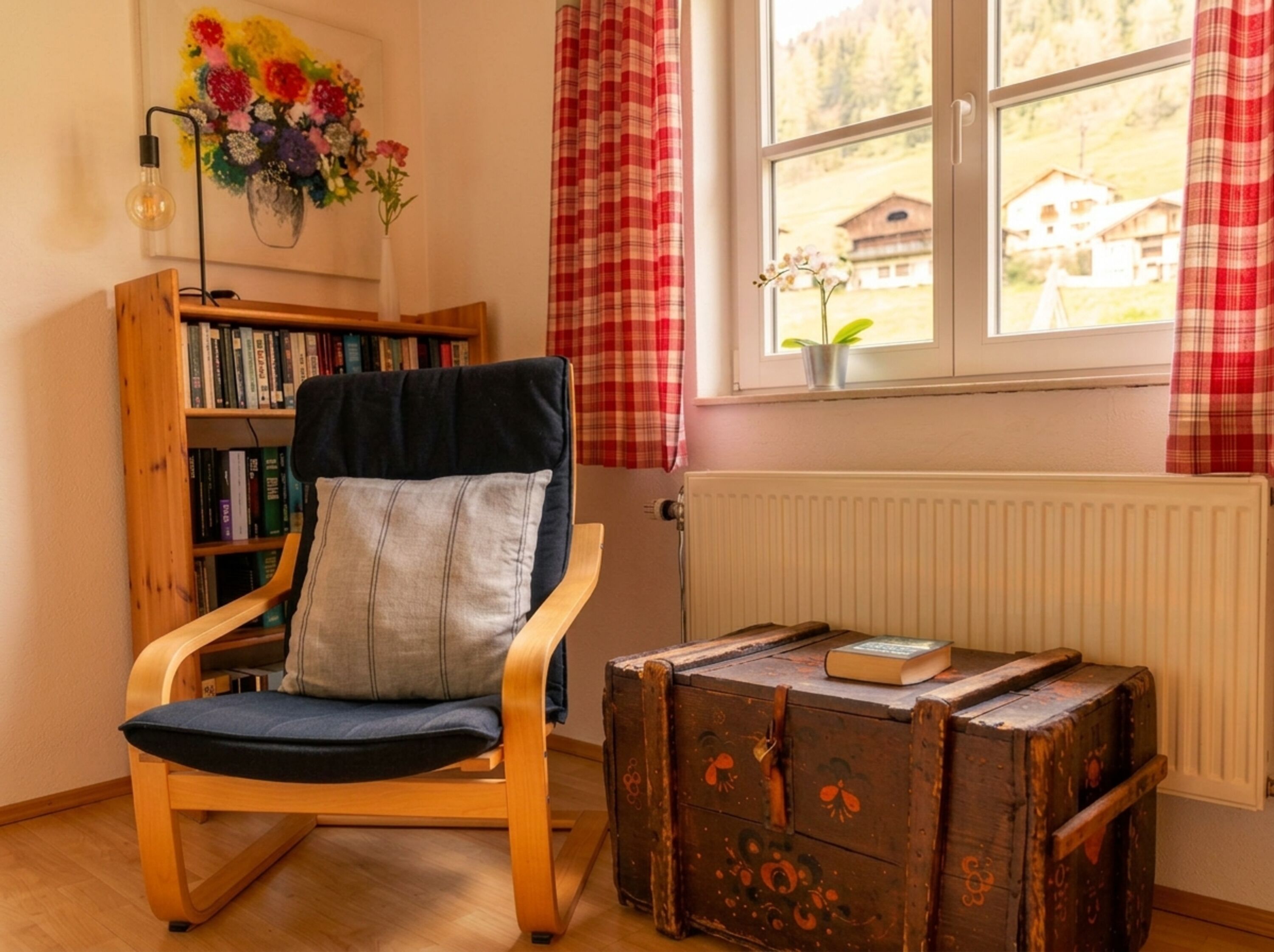 Die liebevoll gestaltete Leseecke im Schlafzimmer bietet einen ruhigen Rückzugsort mit Sessel und ausgewählter Lektüre für entspannte Auszeiten.