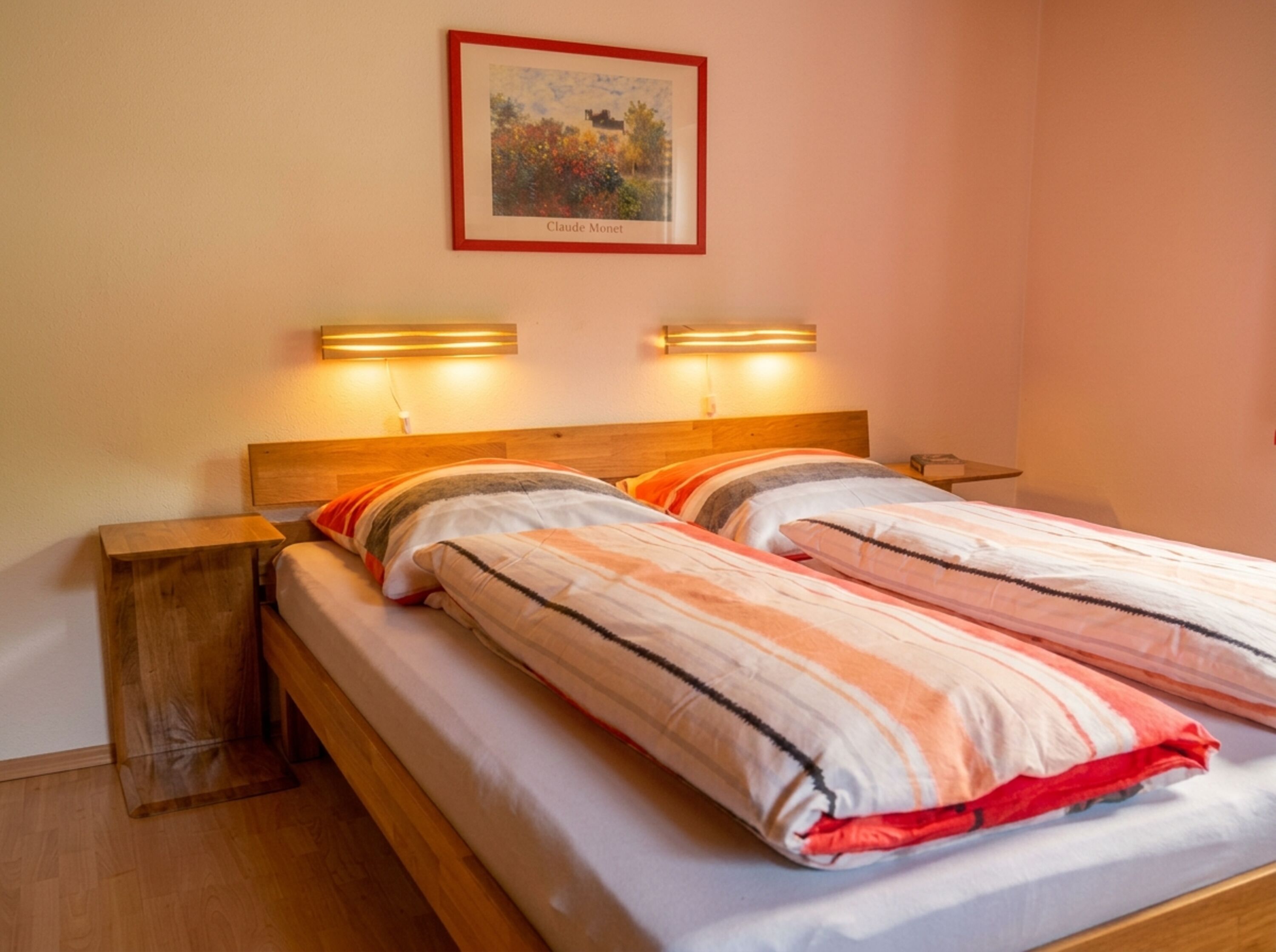 Ein Schlafzimmer zum Ankommen und Abschalten: warmes Licht, ein komfortables Bett und kleine Details wie Büche auf den Nachtischen schaffen eine ruhige , behagliche Atmosphäre