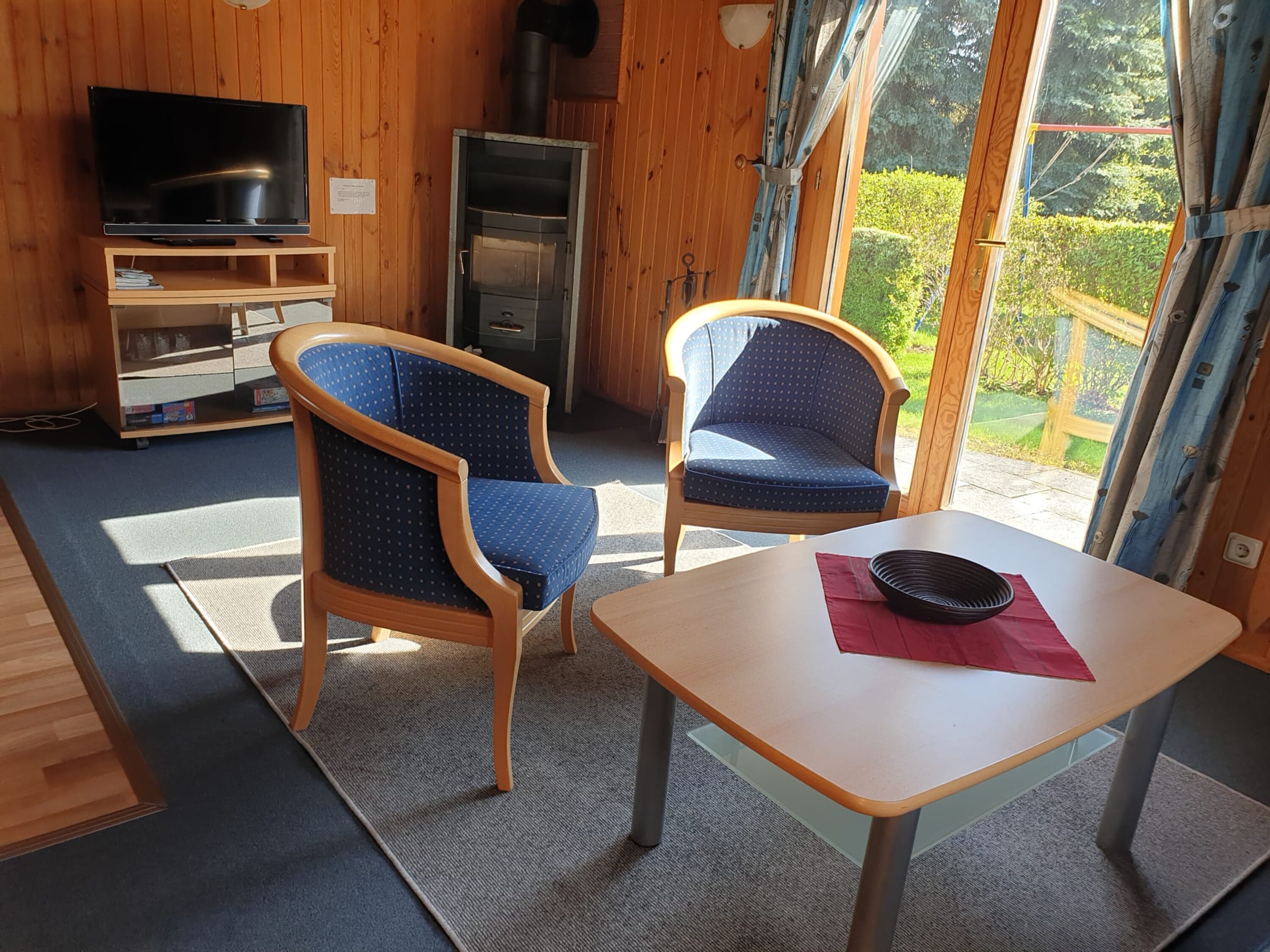 Im Wohnbereich sind Kaminofen und Fernseher. Von hier aus kann man über die Terrasse direkt ins Grüne treten.