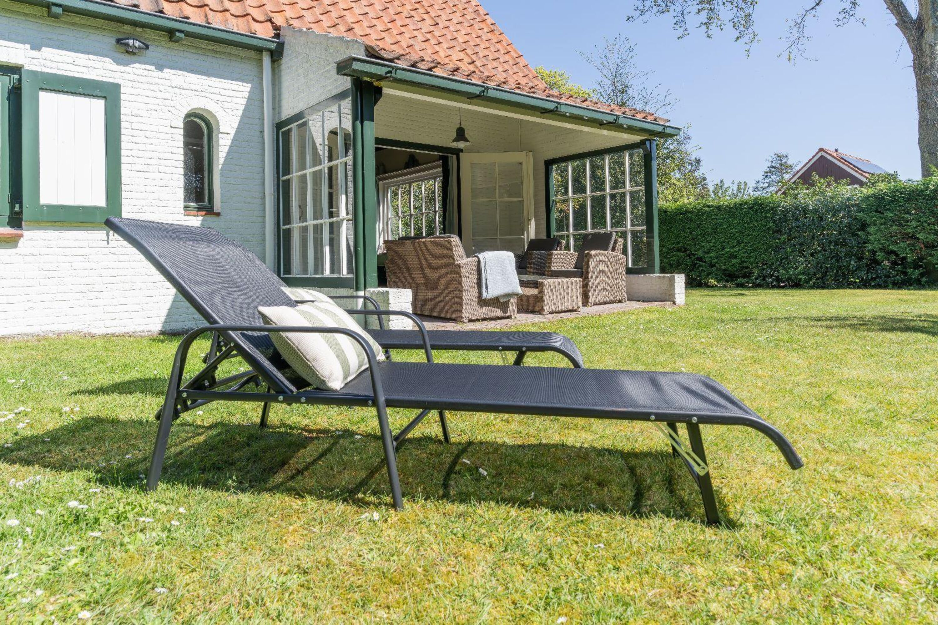 Die überdachte Terrasse mit Gartenmöbel und Sonnenliegen