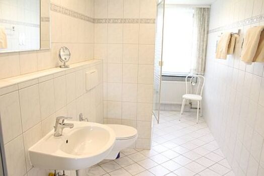 Im großen, hellen Duschbad befinden sich Fön und ein Kosmetikspiegel.