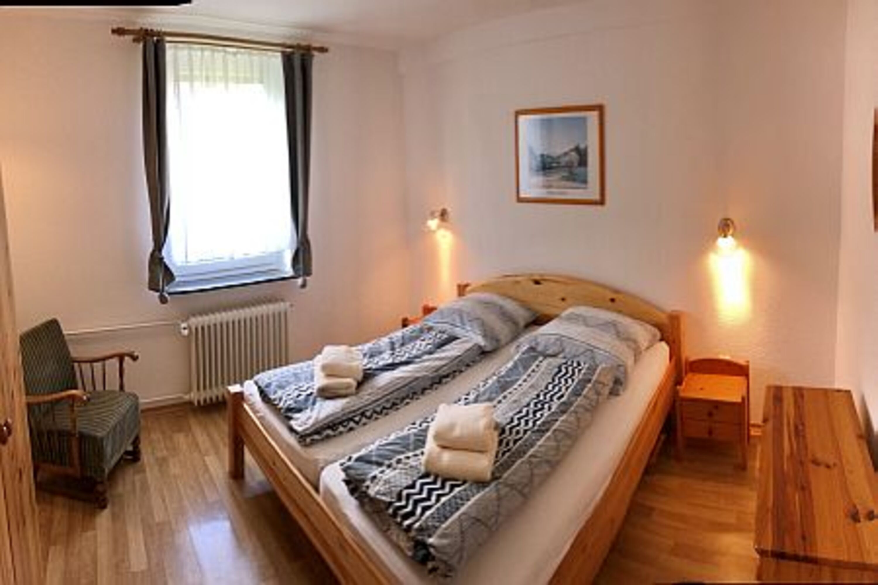 Das zweite Schlafzimmer ist mit einem großen Doppelbett, einem Kleiderschrank einer Kommode und einem gemütlichen Sessel ausgestattet.