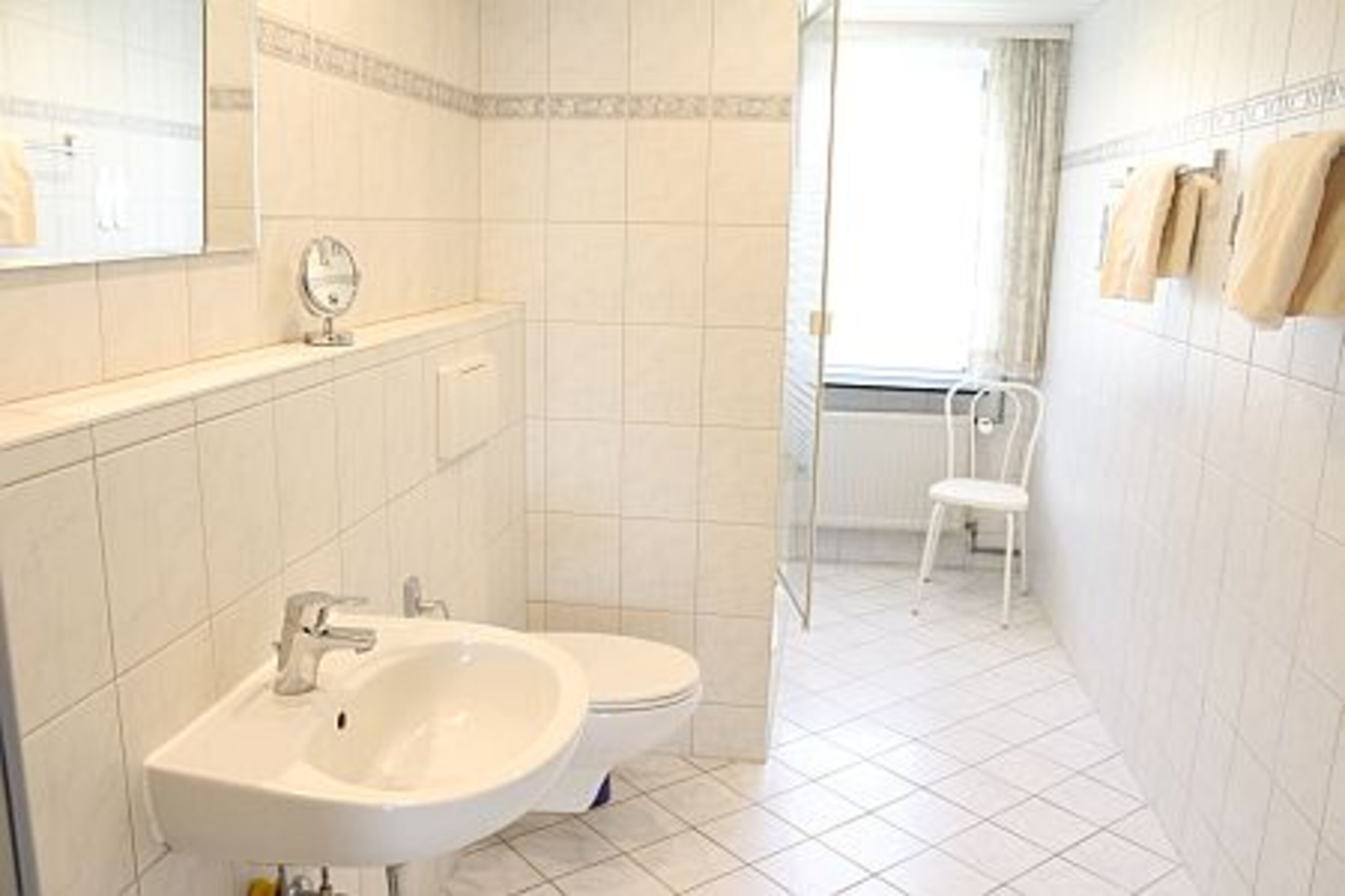 Im großen, hellen Duschbad befinden sich Fön und ein Kosmetikspiegel.