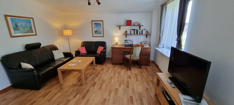 Wohnzimmer mit Schreibtisch und TV