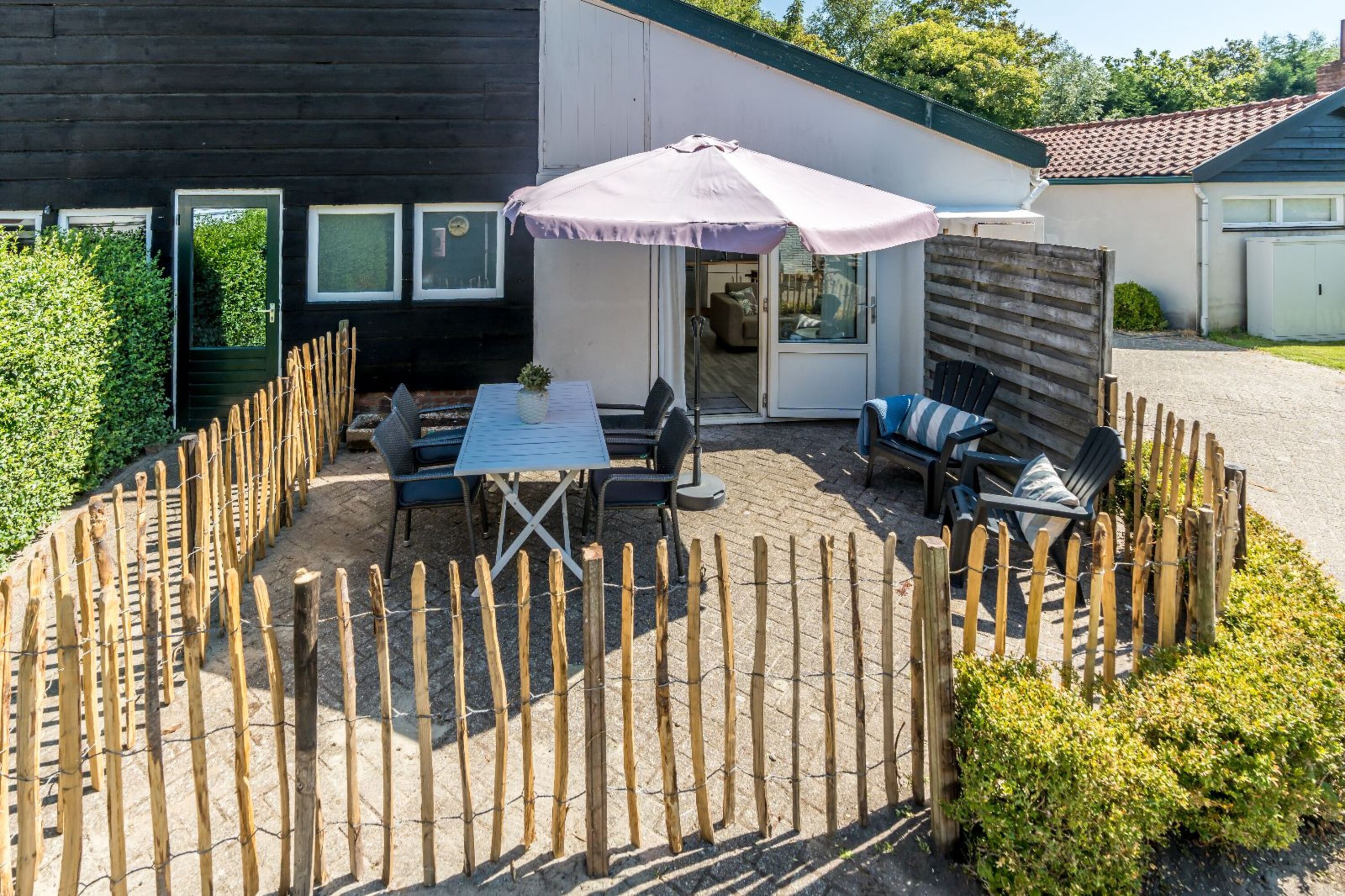 Sonnige, umzäunte Terrasse mit Gartenmöbeln
