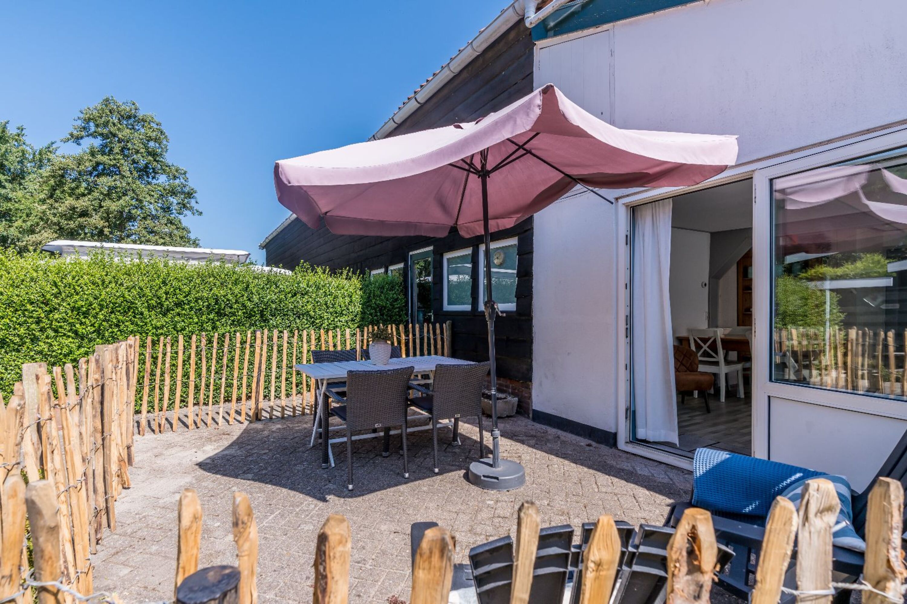 Sonnige Terrase mit Gartengruppe, Sonnenschirm und Grill