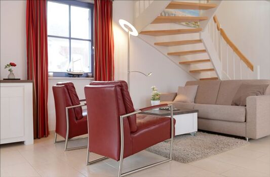 Wohnbereich mit Schlafsofa und Treppe ins Obergeschoss