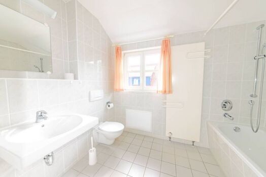 Das große und moderne Bad erwartet Sie mit Badewanne und Fenster.