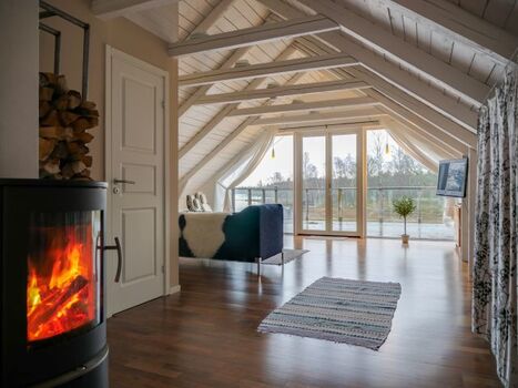 Blick in den Wohnbereich mit Kamin und Seeblick im Obergeschoss