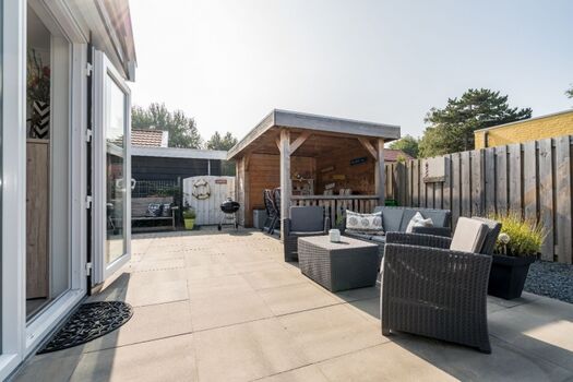 Der sonnige, umzäunte Garten mit Loungeset und Grill