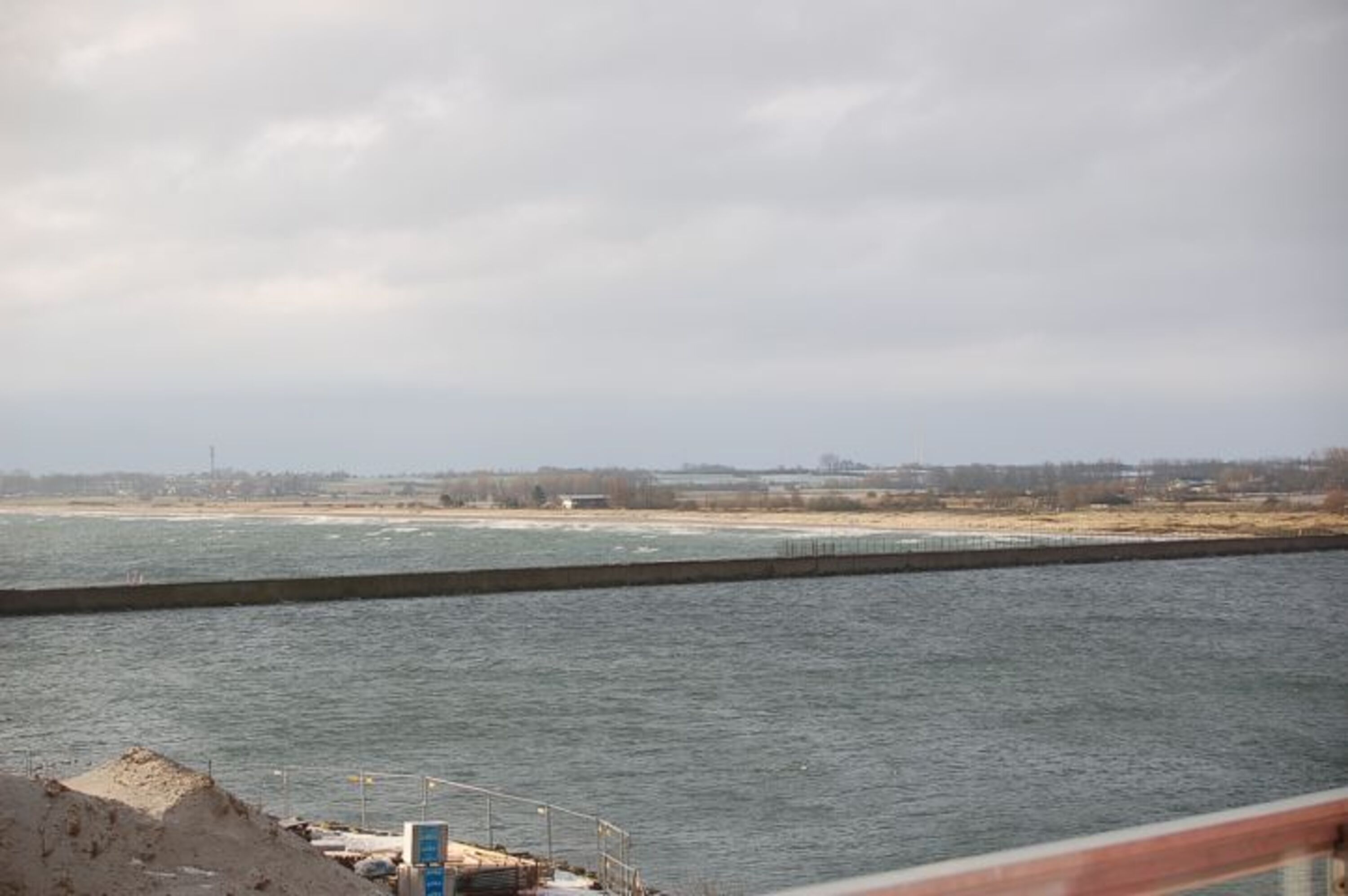 Blick auf die Hafeneinfahrt und den langen Sandstrand mit Hunde, Bade, Kitesurf und FFK Bereichen