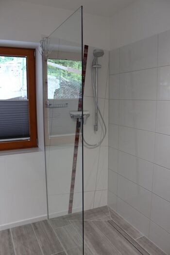 Badezimmer mit ebenerdiger Dusche und Fenster