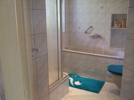 Badezimmer mit Dusche, Badewanne, Waschbecken, WC, Pflegeprodukten