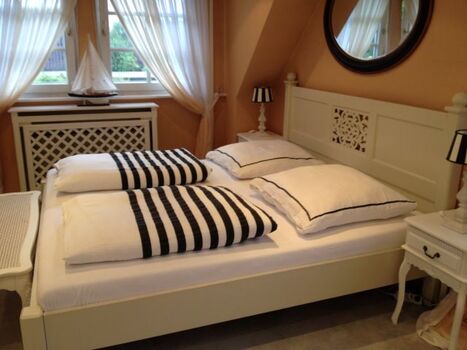 Stimmig bis ins letzte Detail: Schlafzimmer mit großzügigem Doppelbett, Kommode und Holz-Kinderbett