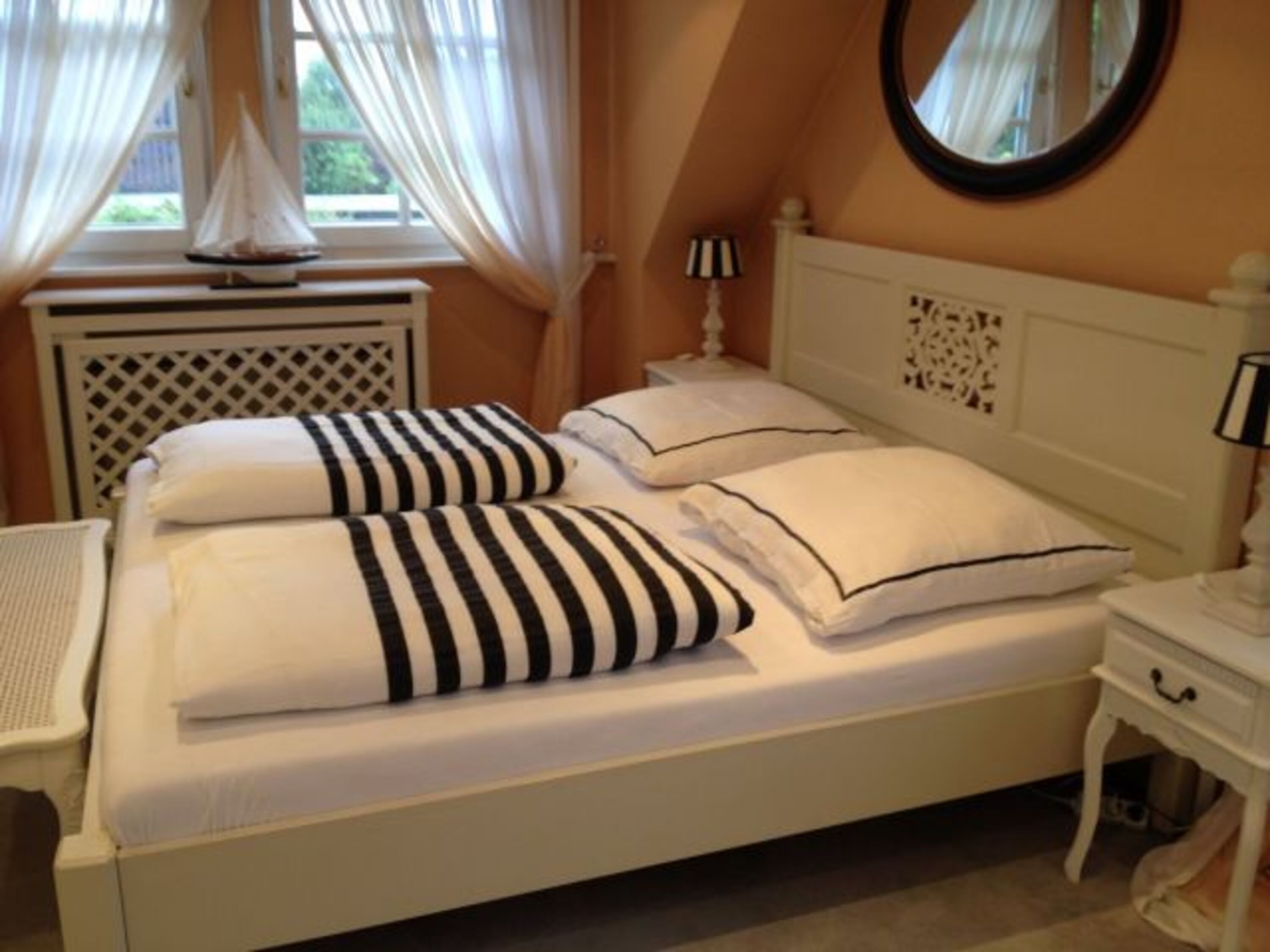 Stimmig bis ins letzte Detail: Schlafzimmer mit großzügigem Doppelbett, Kommode und Holz-Kinderbett