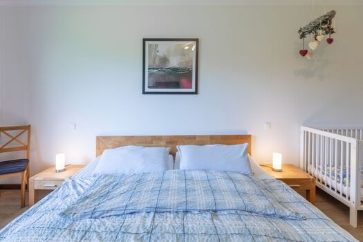 Haus am Deich -  Hauptschlafzimmer mit großem Doppelbett und Babybettchen