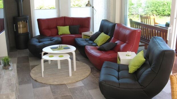 Der Wohnbereich mit hochwertiger und flexibler Couchgarnitur, Kaminofen mit Holzkontingent, grosser Flachbild-TV, Fussbodenheizung, grosse bodentiefe Schiebetüren öffnen den Ausgang zur Süd-Terrasse und dem Garten mit Holzterrasse, Grill, Gartenmöbeln und