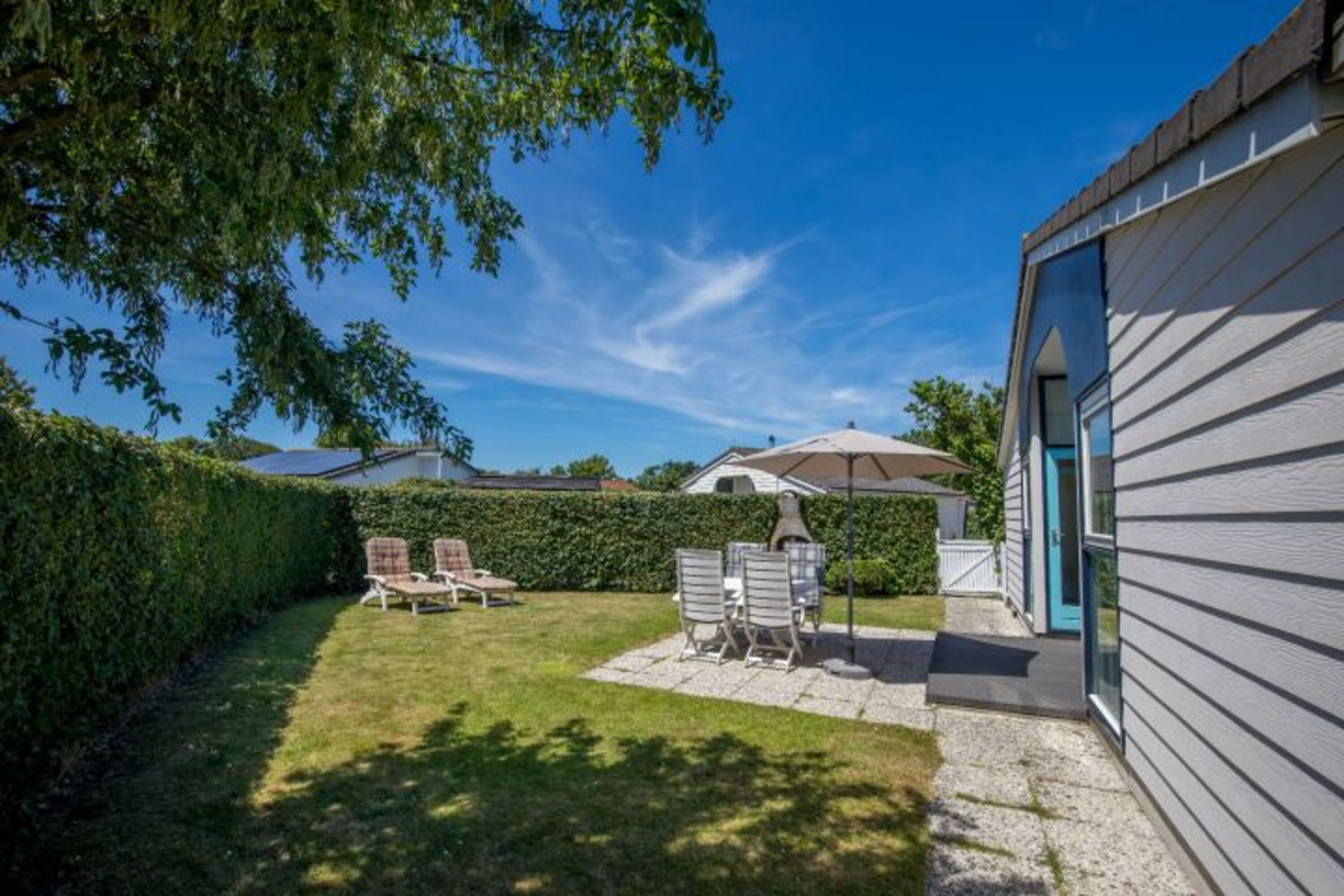 Der sonnige, eingezäunte Garten mit Liegen und Grill
