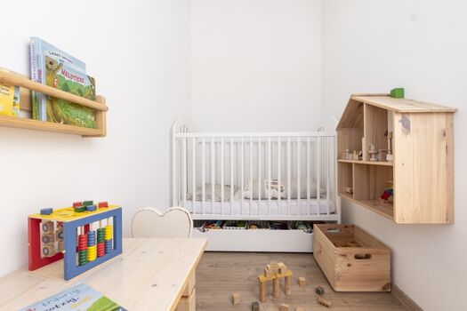 Kinderecke im Familienschlafzimmer mit Einschlaflicht, Sitzgruppe und Bettchen
