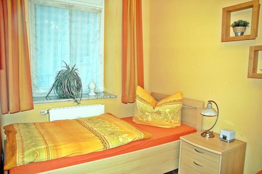 Schlafzimmer mit Fenster und zwei separaten Einzelbetten.