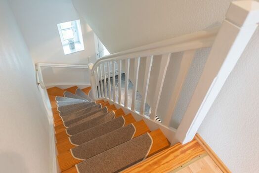 offene Holztreppe mit Teppichstufen ins OG 
