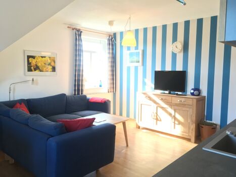 Wohnbereich mit großem Sofa und Sat-TV