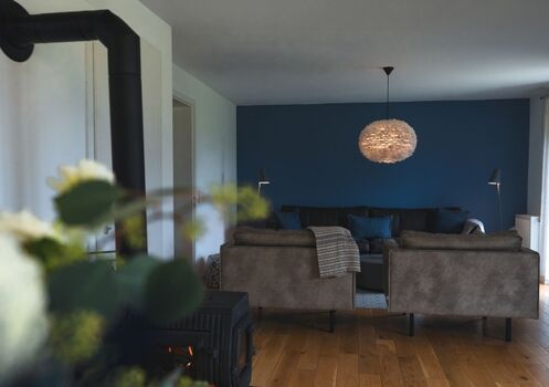 Blauer Wohntraum – stilvolles Interieur mit Ledersofa, bequemen Sesseln und Kamin für gemütliche Stunden