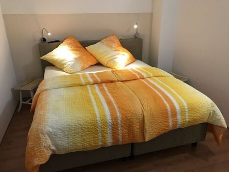 Schlafzimmer im OG mit Boxspringbett, Leselampen und Flat-TV