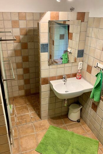 Im Erdgeschoss Badezimmer mit ebenerdiger Dusche, Waschbecken, Fenster und Badewanne.