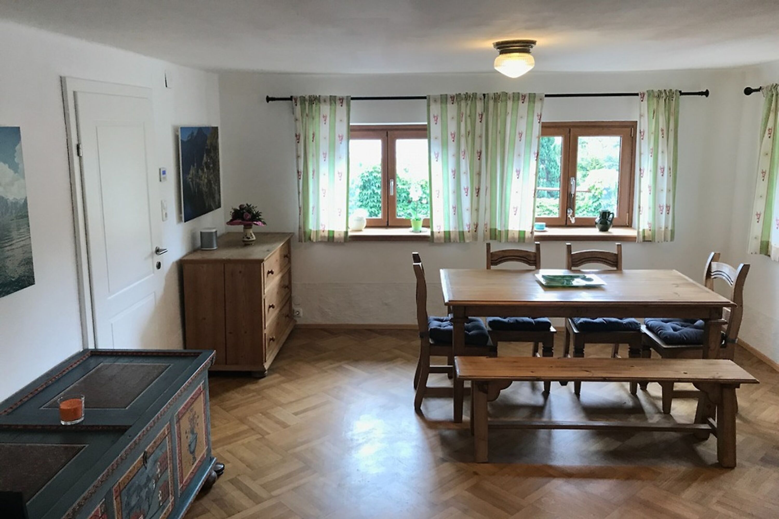Wohnzimmer im unteren Stockwerk mit großem Esstisch und urigen Möbeln & Truhe.