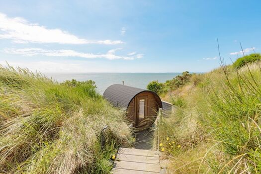 Steg zur Fasssauna und Terrasse mit Strandkorb und Meerblick