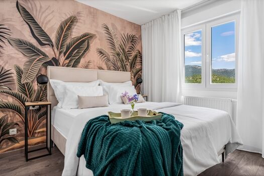 Schlafzimmer Nr. 1 mit einem Queensize-Bett (160 cm x 200 cm), einem Flachbildfernseher und einem eigenen Badezimmer sowie Blick auf den Pool