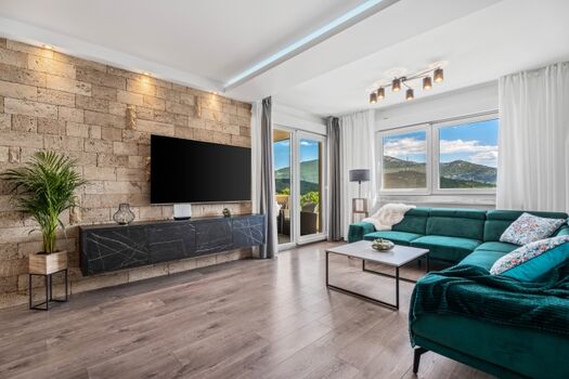 Der Innenraum der Villa BEYBE bietet einen klimatisierten Wohn- und Essbereich mit TV und einen Ausgang zur Lounge-Ecke im Freien mit Blick auf den Poolbereich