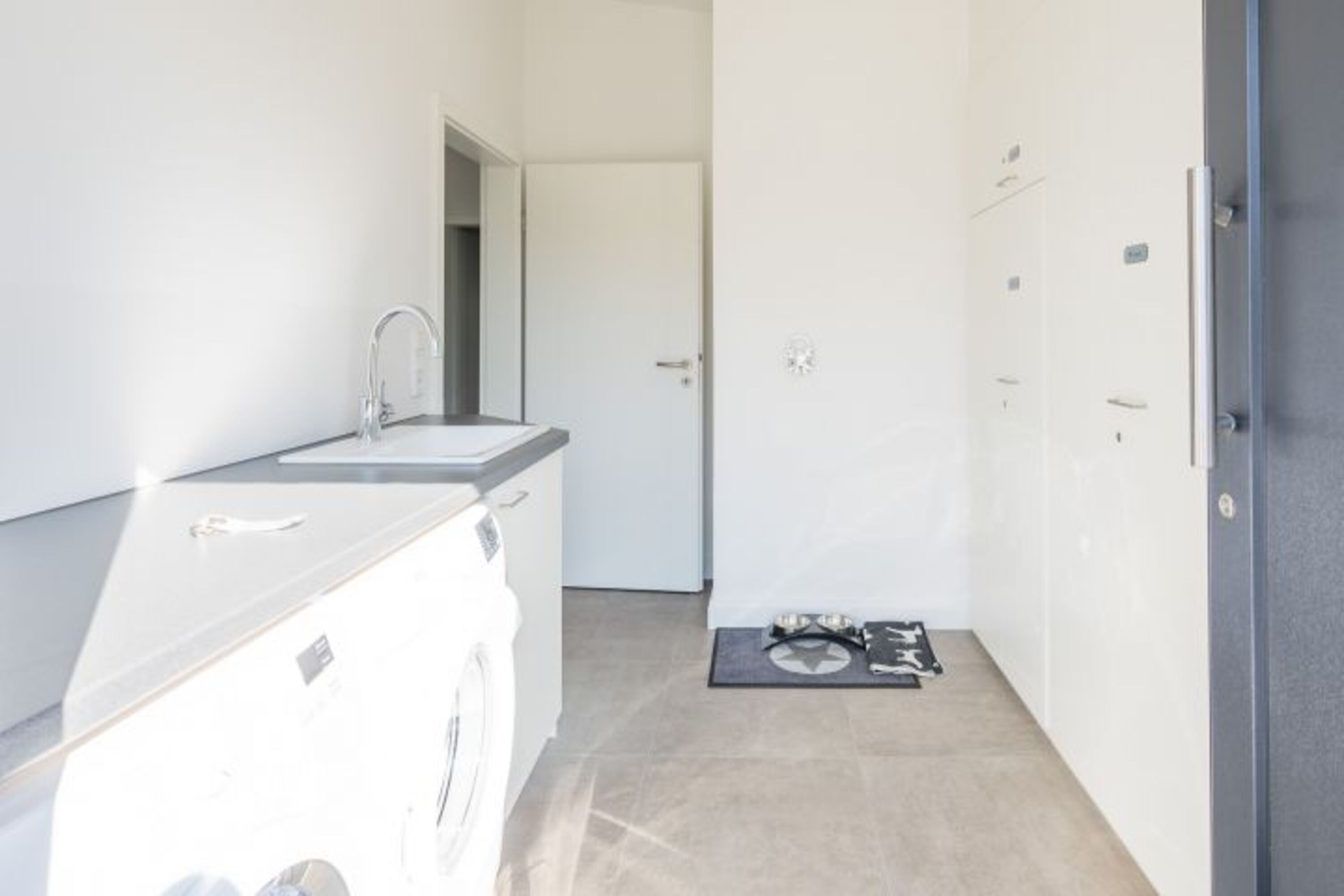 Georgs Huis - Helle Waschküche mit Waschmaschine, Trockner und Waschbecken 